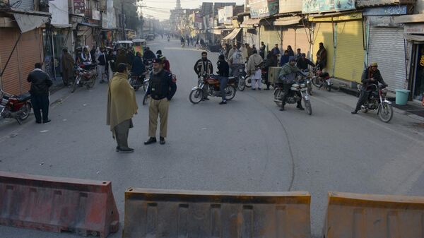 Security officials stand guard on a blocked road leading to a counter-terrorism center where several Pakistani Taliban detainees have taken police officers and others hostage inside the compound, in Bannu, a district in the Pakistan's Khyber Pakhtunkhwa province, Monday, Dec. 19, 2022. - Sputnik India