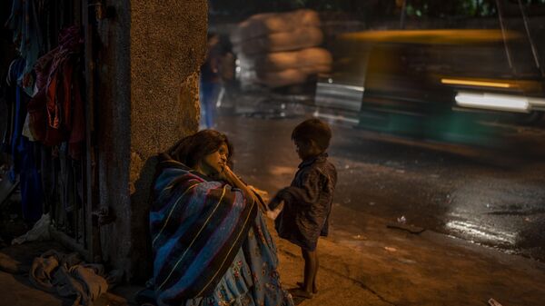 A homeless woman sits by the entrance of a dilapidated shelter in New Delhi, Dec. 30, 2022. - Sputnik India