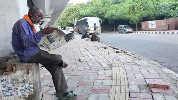 A homeless man reading newspaper early morning near a newspaper selling point at Delhi's I.S.B.T. area - Sputnik India