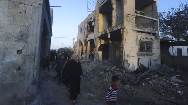 Palestinians walk by a residential building destroyed in an Israeli strike in Rafah, Gaza Strip, Sunday, Feb. 11, 2024 - Sputnik India